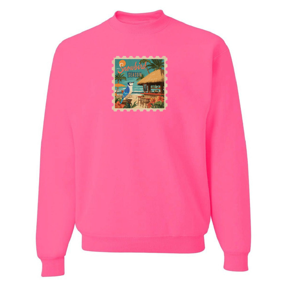 Pink sweatshirt with a beach scene graphic on a white background