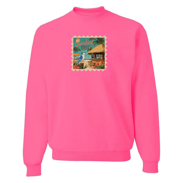 Pink sweatshirt with a beach scene graphic on a white background