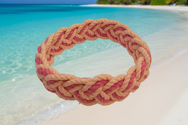 Braided pink and beige headband on a beige background