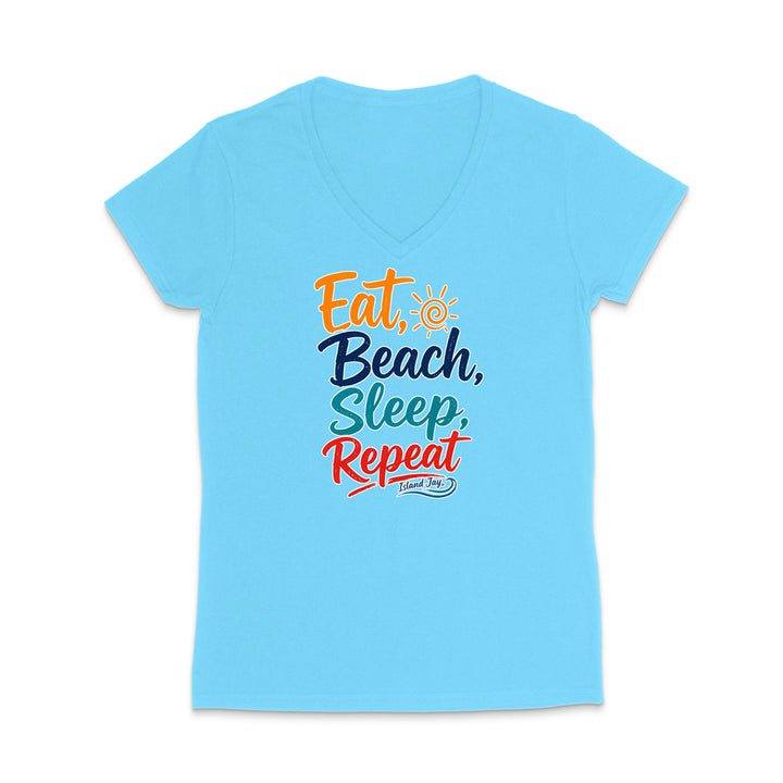 A light blue women's V-neck t-shirt with a colorful graphic on the chest that reads 'Eat, Beach, Sleep, Repeat' in orange, navy, teal, and red lettering, with a small sun icon and 'I Love NY' below.