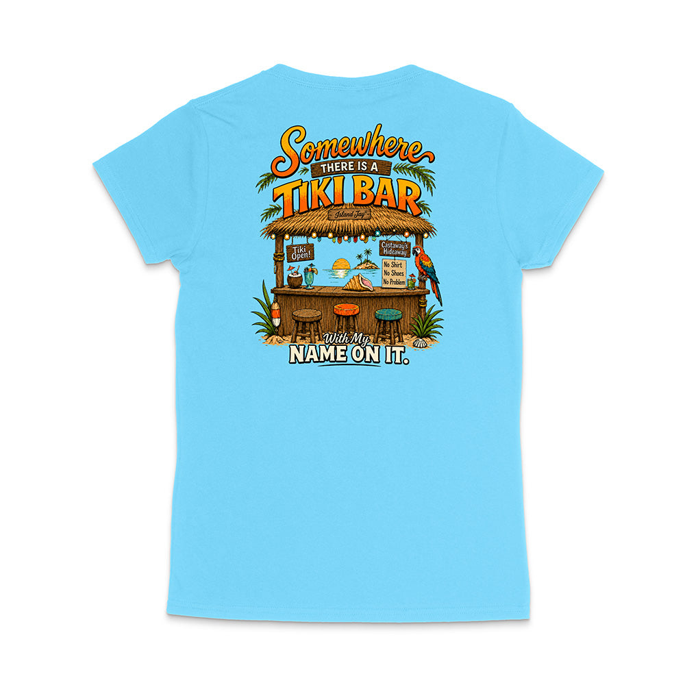 A light blue short-sleeve t-shirt shown from the back, featuring a colorful graphic of a tropical 'Tiki Bar' with the text 'Somewhere there is a TIKI BAR' and 'With my NAME ON IT.'.