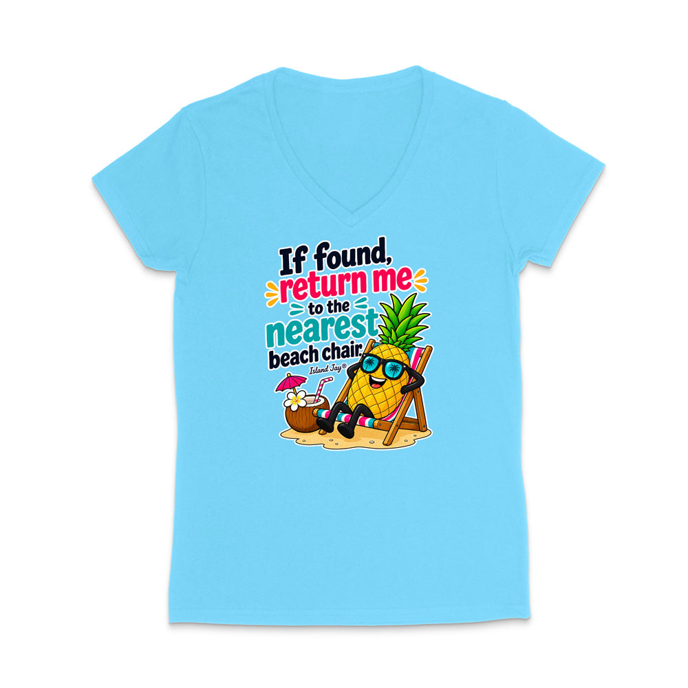A light blue women's V-neck t-shirt with a colorful graphic on the front. The graphic features a pineapple character wearing sunglasses and sitting in a beach chair next to a coconut drink, with the text 'If found, return me to the nearest beach chair.