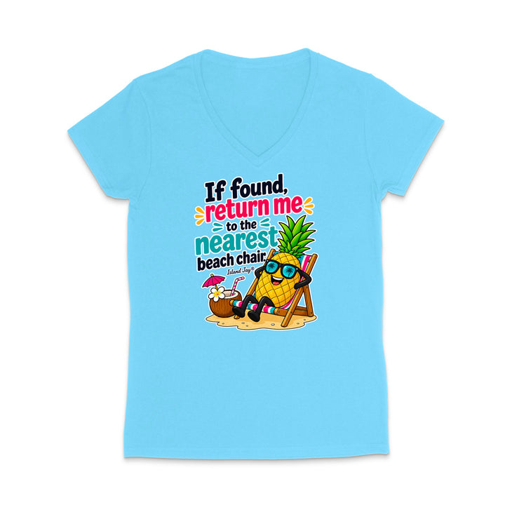 A light blue women's V-neck t-shirt with a colorful graphic on the front. The graphic features a pineapple character wearing sunglasses and sitting in a beach chair next to a coconut drink, with the text 'If found, return me to the nearest beach chair.