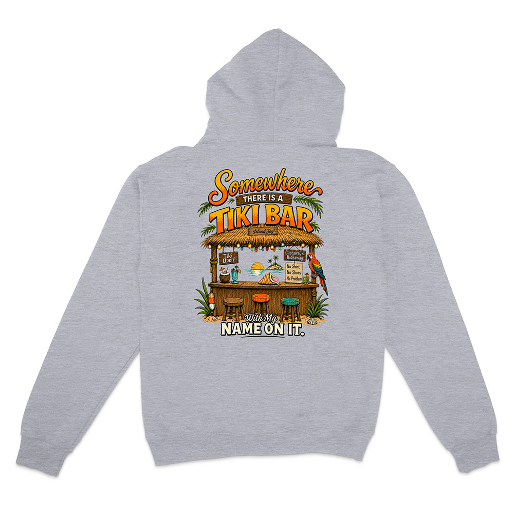 A light heather gray pullover hoodie shown from the back, featuring a colorful graphic print of a tiki bar with the text 'Somewhere There Is A TIKI BAR' and 'NAME ON IT.'.