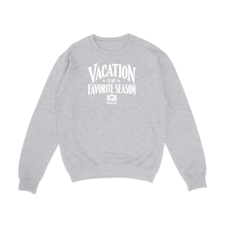 A light heather gray crewneck sweatshirt with a white graphic text print on the chest reading 'VACATION IS MY FAVORITE SEASON' and a small 'it's just me' logo underneath, displayed on a clean white background.