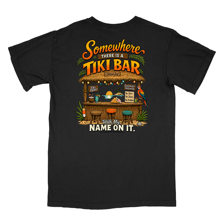 A black short-sleeve t-shirt shown from the back, featuring a large graphic print of a tropical tiki bar with the text 'Somewhere THERE IS A TIKI BAR' and 'with my NAME ON IT.'.