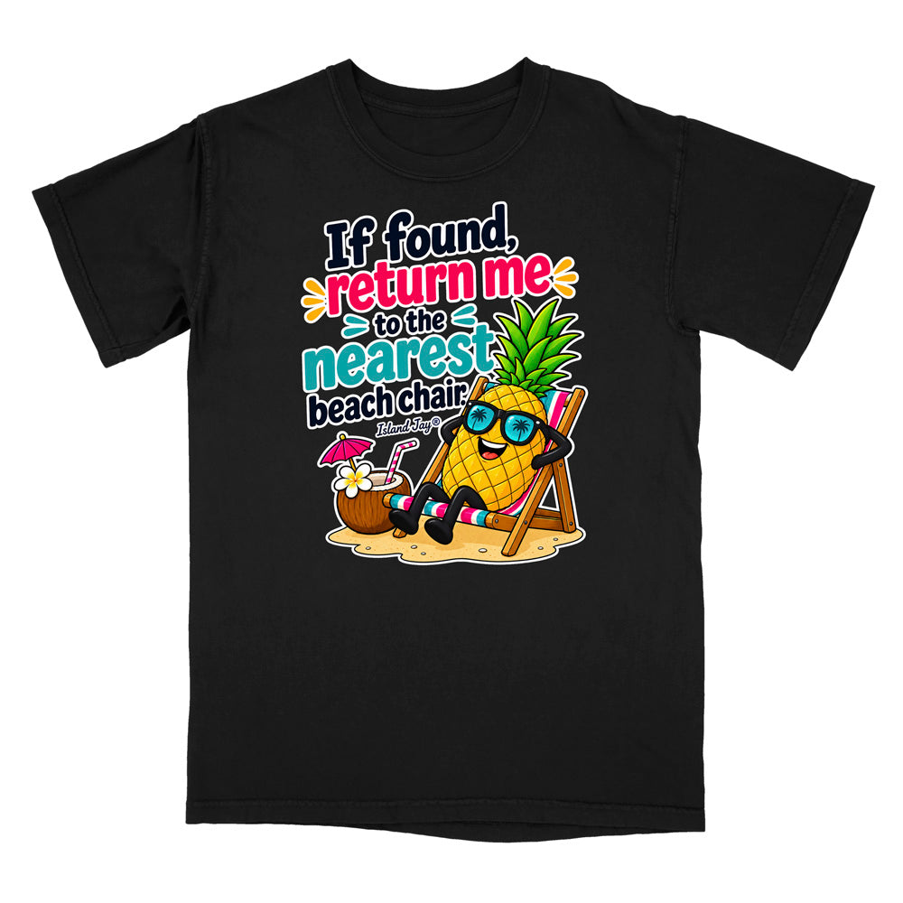 A black short-sleeve crewneck t-shirt featuring a colorful cartoon graphic of a pineapple wearing sunglasses and sitting in a beach chair next to a coconut drink, with the text 'If found, return me to the nearest beach chair.'.