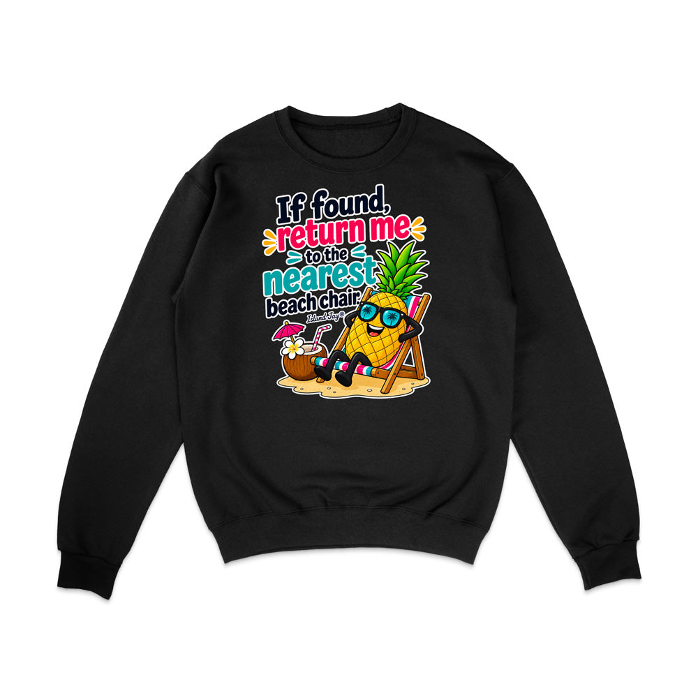 A black crewneck sweatshirt with a colorful graphic print on the front. The graphic features a pineapple wearing sunglasses and a beach chair next to a coconut drink, with the text 'If found, return me to the nearest beach chair'.