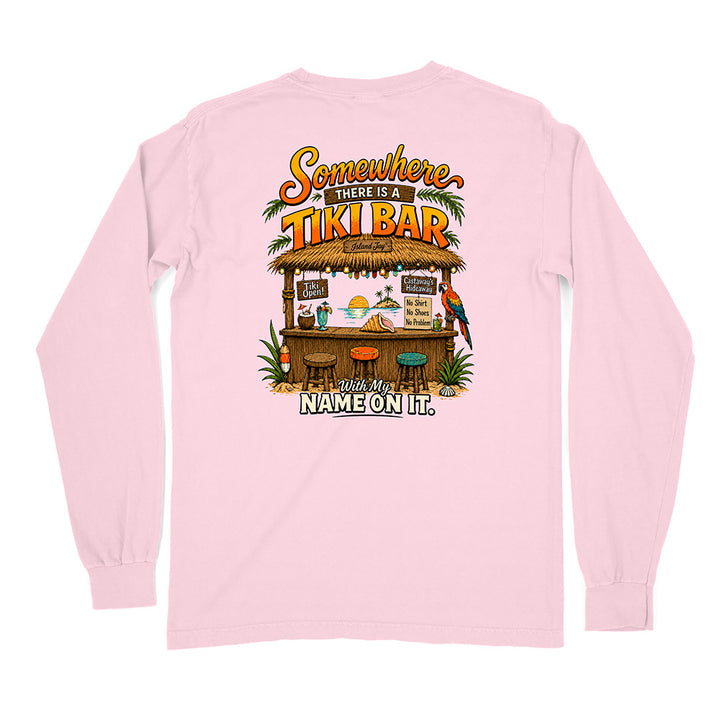 A light pink long-sleeve t-shirt shown from the back, featuring a colorful graphic of a tropical tiki bar with the text 'Somewhere THERE'S A TIKI BAR' and 'with my NAME ON IT.'.
