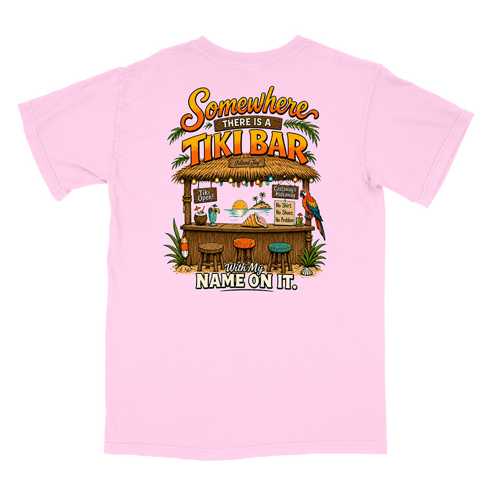A light pink short-sleeve t-shirt with a colorful graphic on the back featuring a tiki bar illustration and the text 'Somewhere THERE IS A TIKI BAR With My NAME ON IT.'.