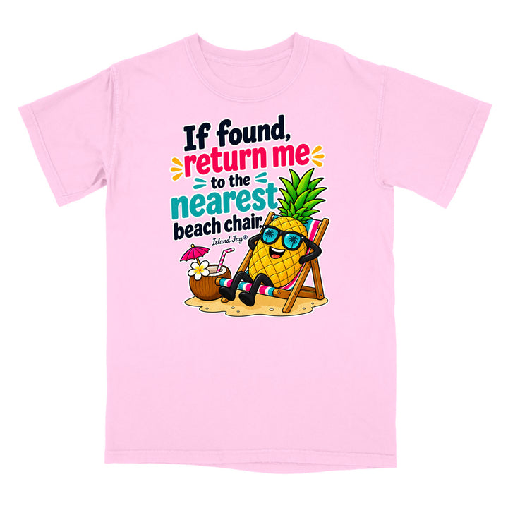 A light pink short-sleeve crewneck t-shirt featuring a colorful graphic of a cartoon pineapple wearing sunglasses and relaxing in a beach chair next to a coconut drink, with the text 'If found, return me to the nearest beach chair' and 'Island Style'.