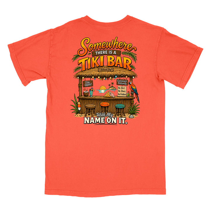 A coral orange short-sleeve t-shirt shown flat against a white background, featuring a colorful graphic of a tiki bar with the text 'Somewhere THERE IS A TIKI BAR' and 'Put My NAME ON IT.'.