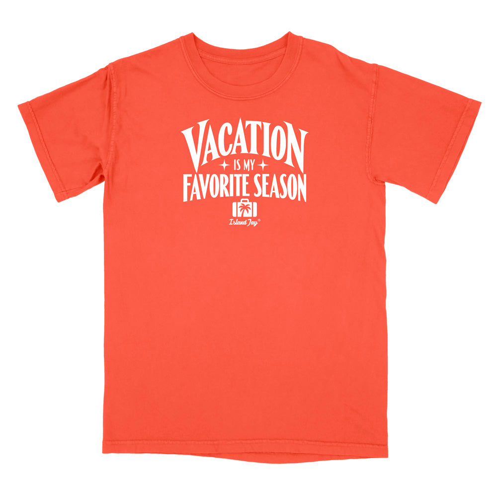 A coral orange short-sleeve t-shirt with a white graphic print on the front that reads 'VACATION IS MY FAVORITE SEASON' with a small 'Deluxe Dog' logo underneath, displayed on a clean white background.