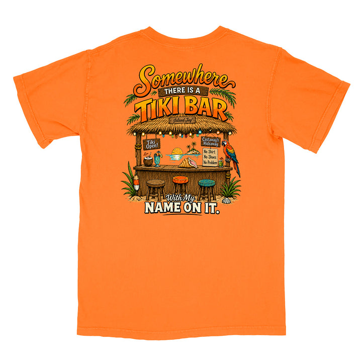 An orange short-sleeve t-shirt with a large graphic print on the back featuring a tropical tiki bar scene and the text 'Somewhere there is a TIKI BAR. Your name will be on it.