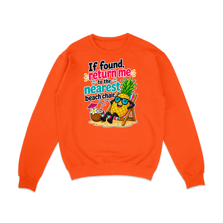 An orange crewneck sweatshirt featuring a colorful graphic print of a pineapple wearing sunglasses and reclining on a beach chair next to a coconut drink, with the text 'If found, return me to the nearest beach chair'.