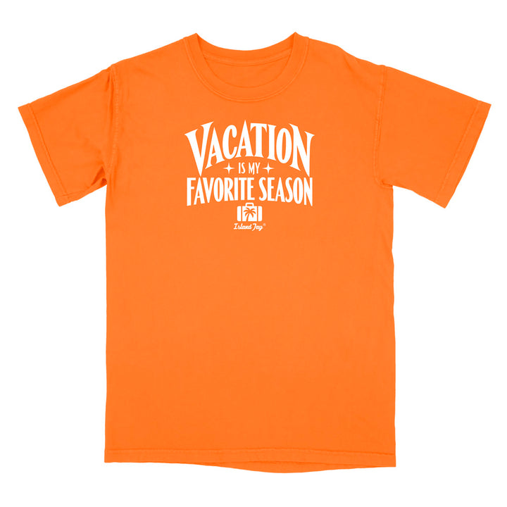 A bright orange short-sleeve t-shirt with a white graphic print on the front that reads 'VACATION IS MY FAVORITE SEASON' with a small camera icon and 'Delilah Dog' logo underneath, shown on a plain white background.