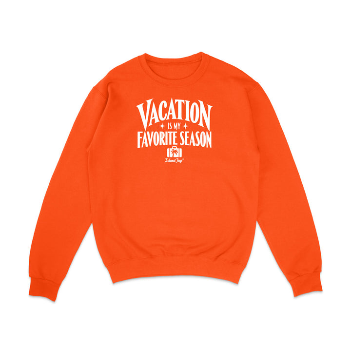 An orange crewneck sweatshirt with a white graphic text print reading 'VACATION IS MY FAVORITE SEASON' and a small 'I'm Always' logo underneath, displayed on a clean white background.