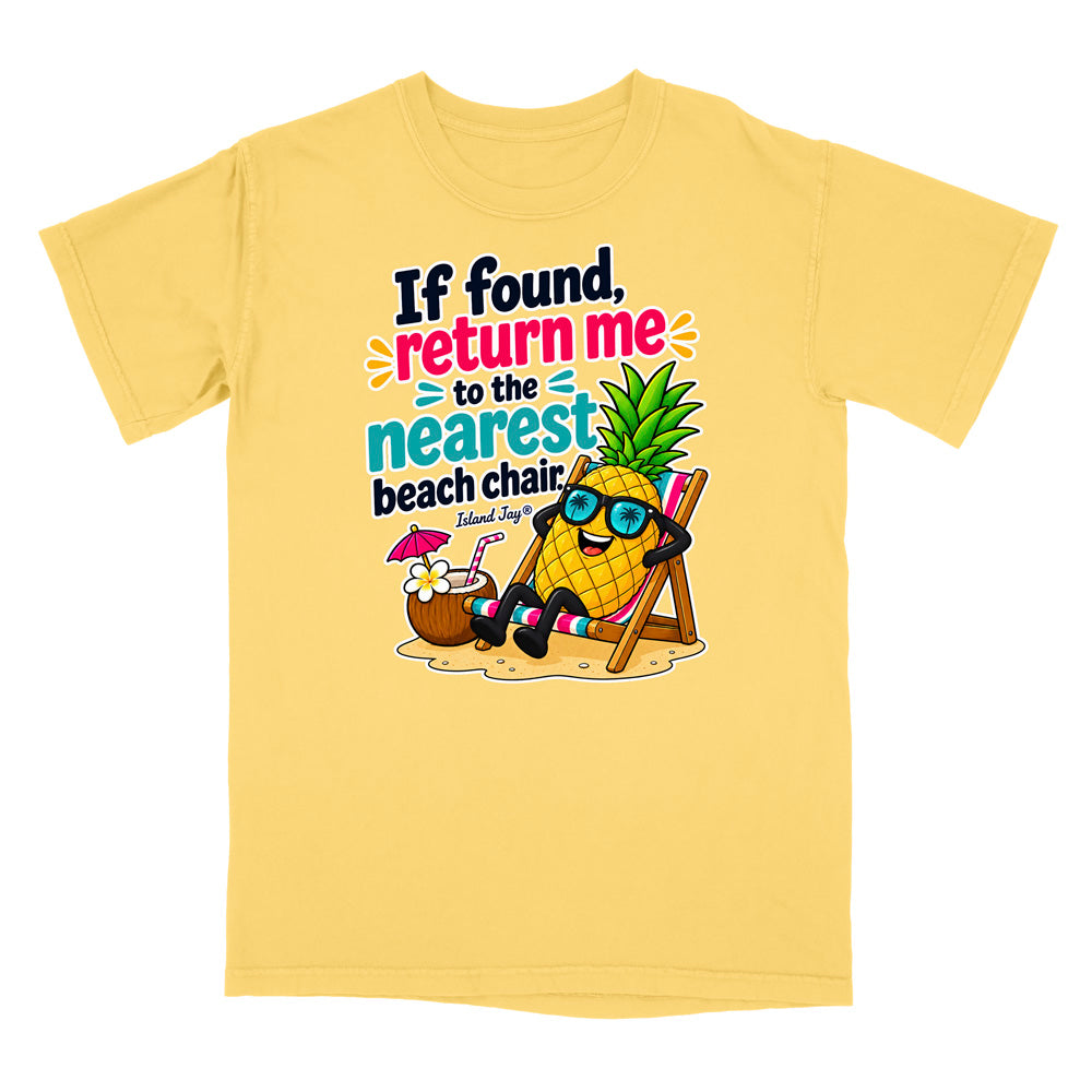 A light yellow short-sleeve t-shirt with a colorful graphic of a pineapple character wearing sunglasses and relaxing in a beach chair on a sandy beach, with the text 'If found, return me to the nearest beach chair. Island Joes'.