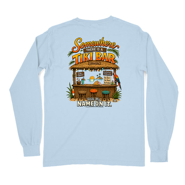 A light blue long-sleeve t-shirt shown from the back, featuring a colorful graphic print of a tropical tiki bar with the text 'Somewhere There Is A TIKI BAR' and 'With My NAME ON IT.'.
