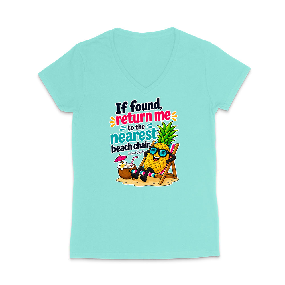 A light aqua V-neck t-shirt with a colorful graphic on the front. The graphic features a pineapple character wearing sunglasses and sitting in a beach chair on a sandy surface, next to a coconut drink, with the text 'If found, return me to the nearest beach chair'.