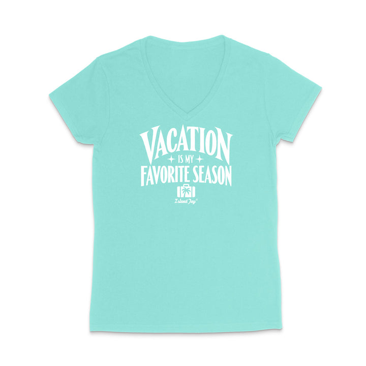 A light aqua V-neck t-shirt with a white graphic print that reads 'VACATION IS MY FAVORITE SEASON' and a small 'Tulum Trip' logo underneath, displayed on a clean white background.