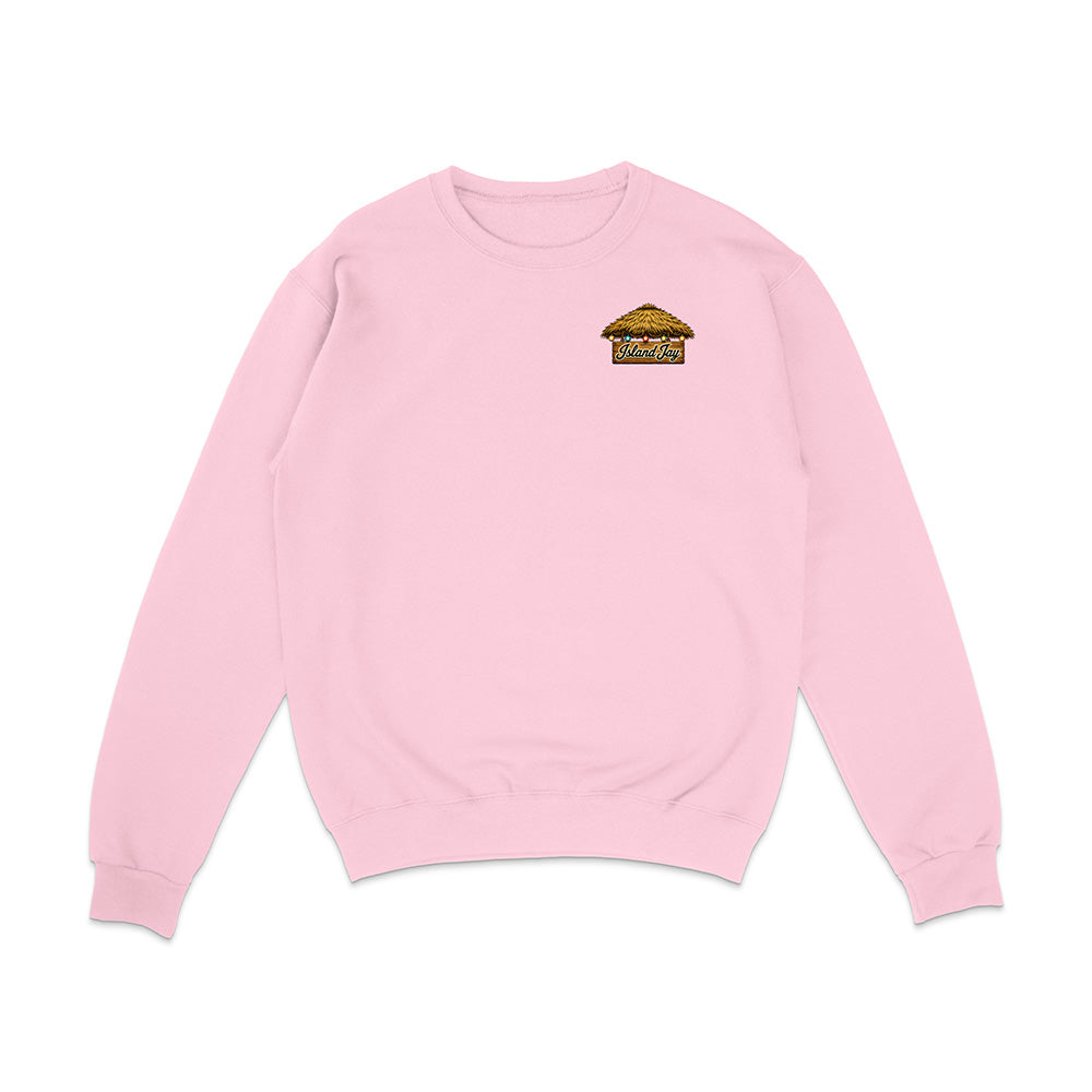 A light pink crewneck sweatshirt with a small graphic on the left chest featuring the word 'ISLAND' in red and a small illustration below it, displayed on a clean white background.