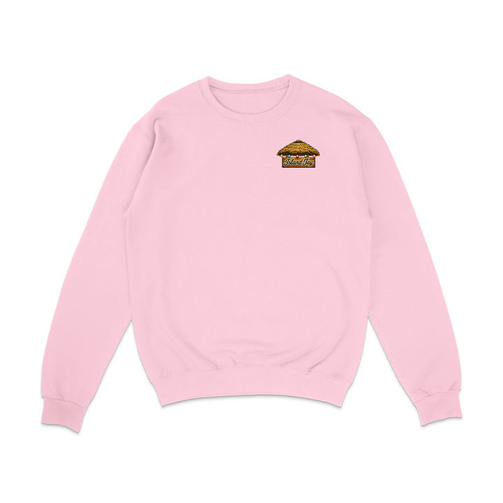A light pink crewneck sweatshirt with a small graphic on the left chest featuring the word 'ISLAND' in red and a small illustration below it, displayed on a clean white background.