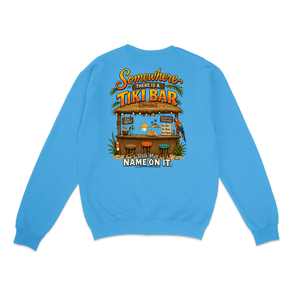 A bright blue crewneck sweatshirt shown from the back, featuring a large graphic print of a tropical 'Tiki Bar' with parrots and the text 'Somewhere there is a TIKI BAR' and 'Make my name on it.'.