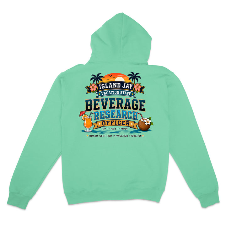 A mint green hoodie shown from the back, featuring a colorful graphic print that reads 'ISLAND JAY BEVERAGE RESEARCH OFFICER' with tropical illustrations including palm trees, a sunset, a cocktail, and a coconut drink.