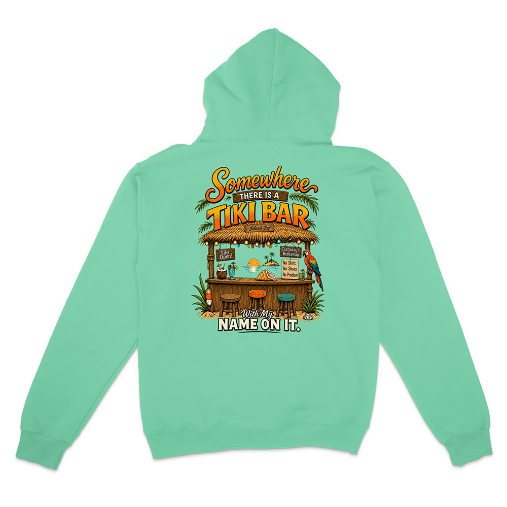 A mint green hoodie shown from the back, featuring a colorful graphic of a tiki bar with the text 'Somewhere There Is A TIKI BAR' and 'NAME ON IT.'.