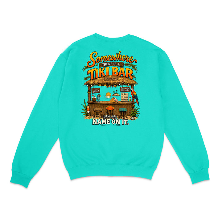 A turquoise crewneck sweatshirt shown from the back, featuring a colorful graphic of a tropical tiki bar with the text 'Somewhere THERE IS A TIKI BAR' and 'Wit My NAME ON IT.'.