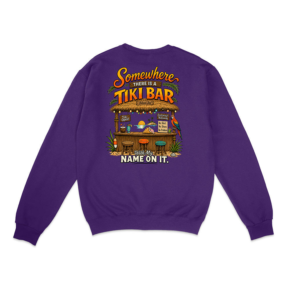 A purple crewneck sweatshirt shown from the back, featuring a colorful graphic of a tropical tiki bar with the text 'Somewhere THERE IS A TIKI BAR and my NAME ON IT.'.