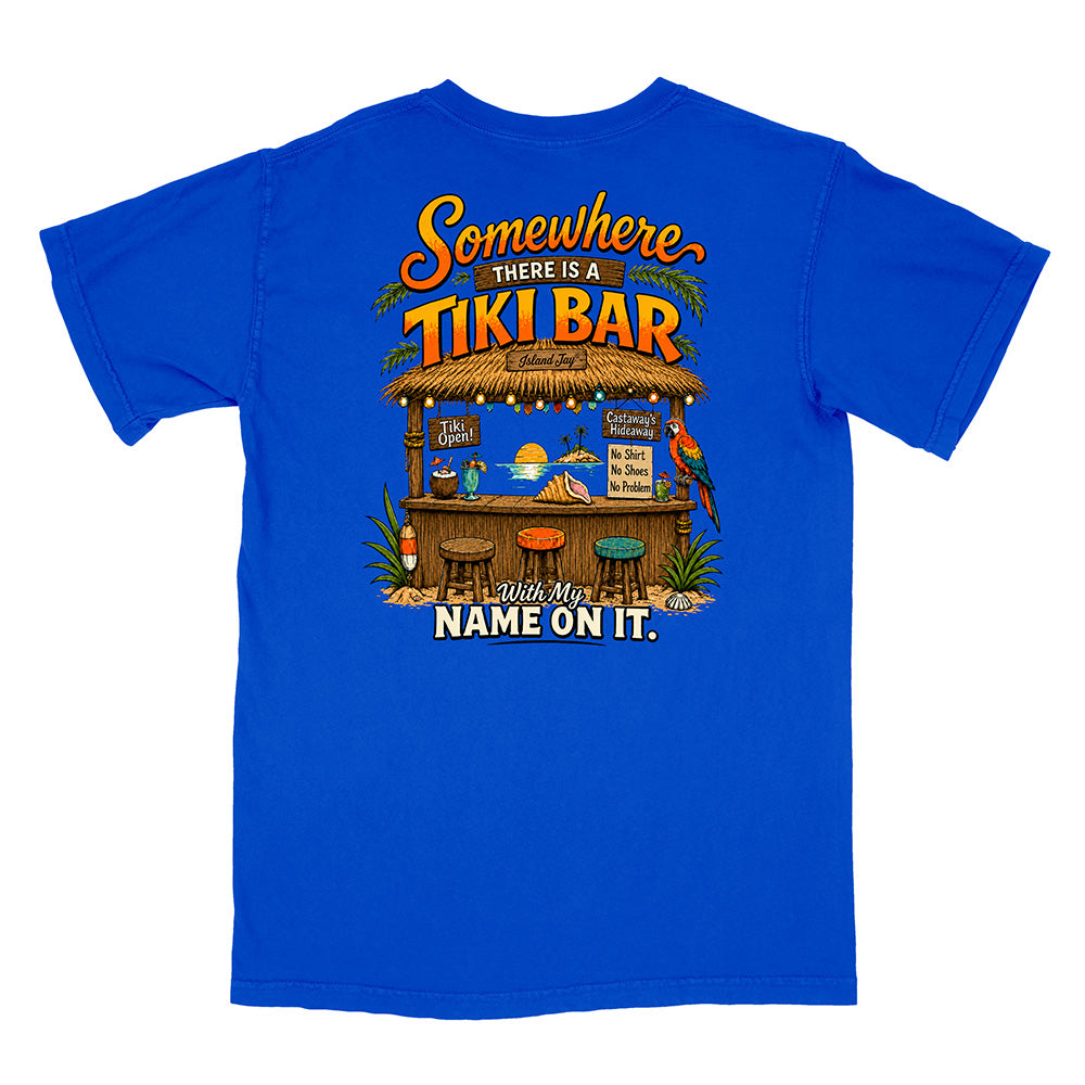 A royal blue short-sleeve t-shirt with a large graphic print on the back featuring a tropical tiki bar scene and the text 'Somewhere THERE IS A TIKI BAR with my NAME ON IT.'.