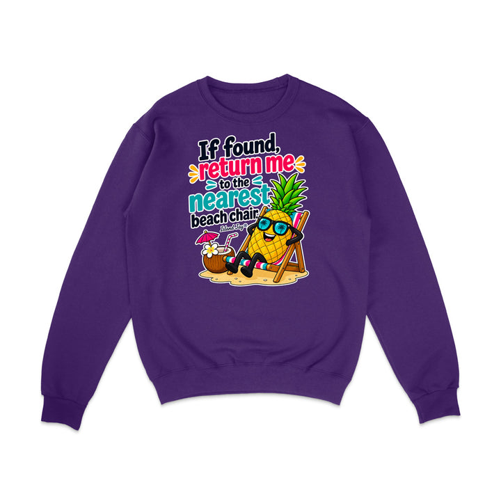 A purple crewneck sweatshirt with a colorful graphic on the chest featuring a pineapple character wearing sunglasses and a beach chair next to a coconut drink, with the text 'If found, return me to the nearest beach chair'.