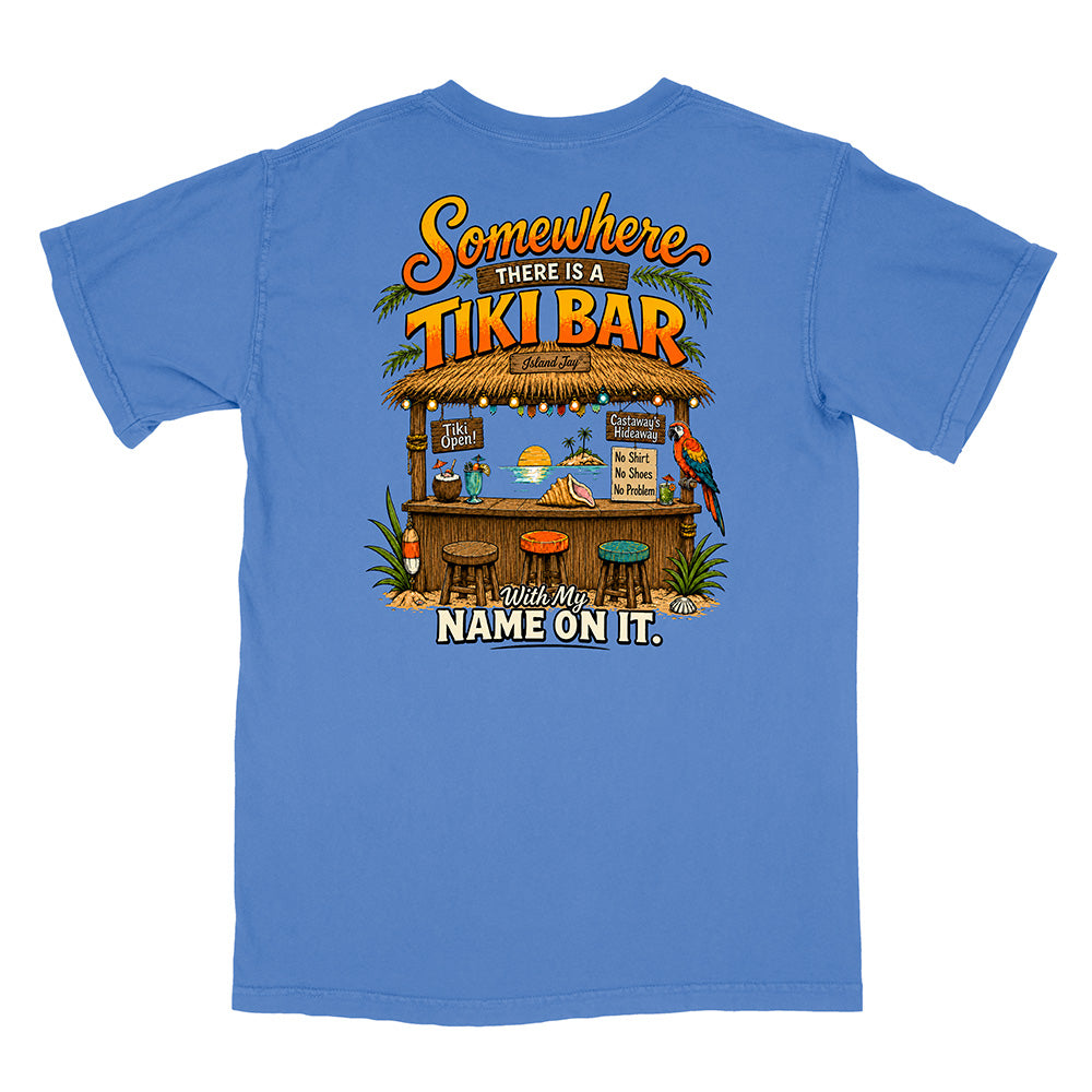 A blue short-sleeve t-shirt shown flat against a white background, featuring a large graphic print on the back with a tropical tiki bar illustration and the text 'Somewhere THERE IS A TIKI BAR With My NAME ON IT.'.