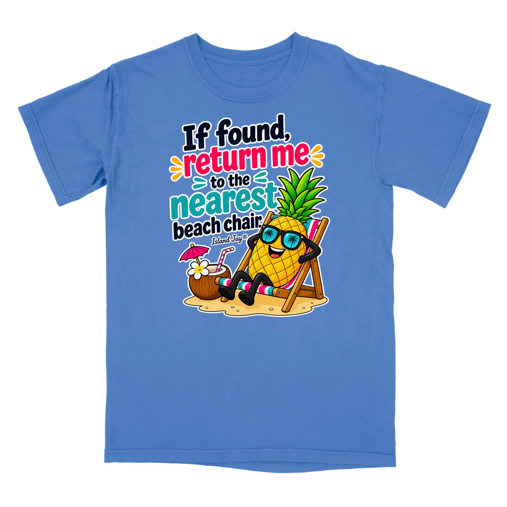 A blue short-sleeve crewneck t-shirt featuring a colorful graphic of a pineapple wearing sunglasses and relaxing in a beach chair next to a coconut drink, with the text 'If found, return me to the nearest beach chair' printed on the front.