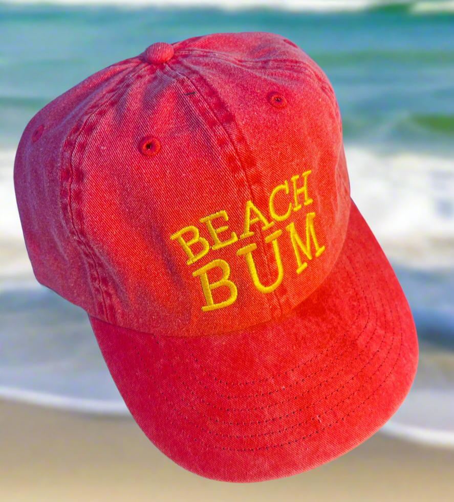 Red cap with 'BEACH BUM' text on a beach background
