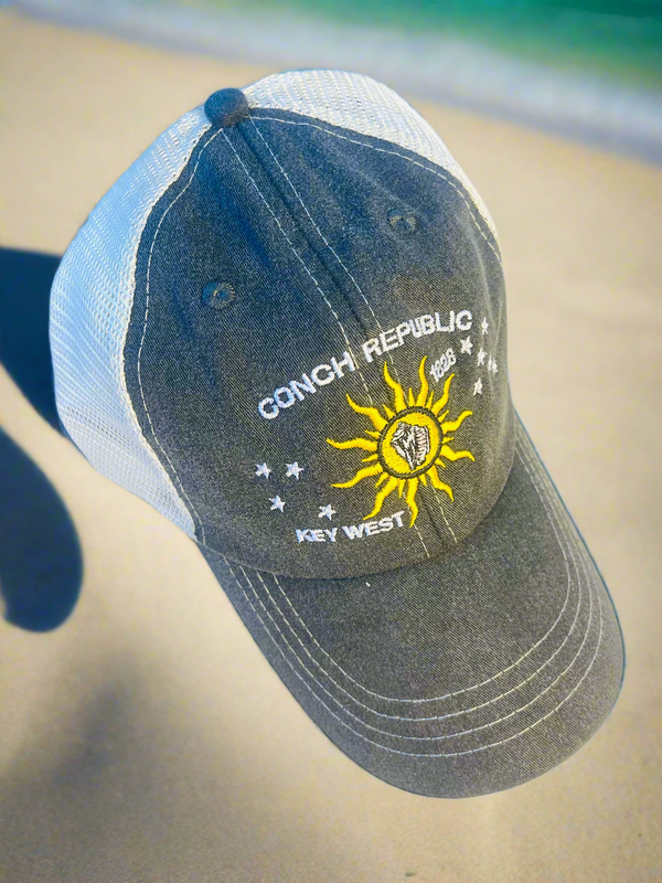 Cap with 'Conch Republic Key West' text and sun design on a beach.