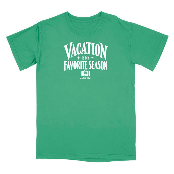 A green short-sleeve t-shirt with a white graphic print on the front that reads 'VACATION IS MY FAVORITE SEASON' with a small 'Delicious Dog' logo underneath, displayed on a solid white background.