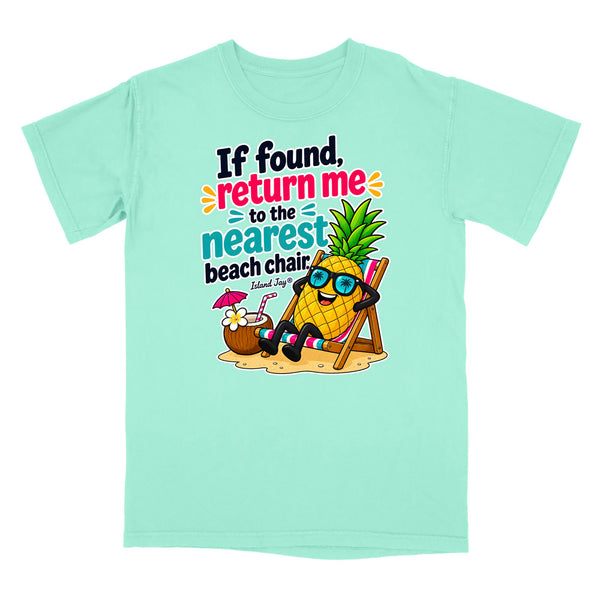 A mint green short-sleeve t-shirt with a colorful graphic of a pineapple relaxing in a beach chair on the front, accompanied by the text 'If found, return me to the nearest beach chair. Island Jazzy'.