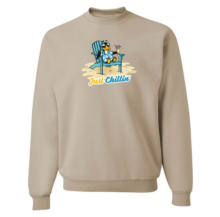 Beige sweatshirt with a graphic of s cartoon penguin on a beach chair and 'Just Chillin' text.