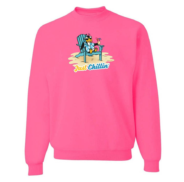 Pink sweatshirt with a graphic of a cartoon penguin on a beach chair and 'Just Chillin'' text.