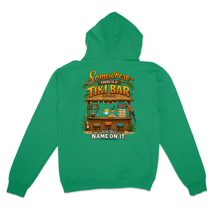 A green pullover hoodie shown from the back, featuring a colorful graphic of a tropical 'Tiki Bar' with parrots, drinks, and the text 'Somewhere THERE IS A TIKI BAR. NAME ON IT.