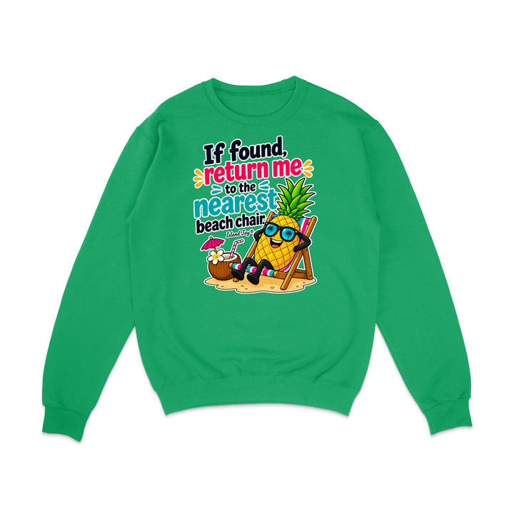A bright green crewneck sweatshirt with a colorful graphic on the front. The graphic features a cartoon pineapple wearing sunglasses and reclining in a beach chair next to a coconut drink with a pink umbrella, with the text 'If found, return me to the nearest beach chair' in stylized fonts.