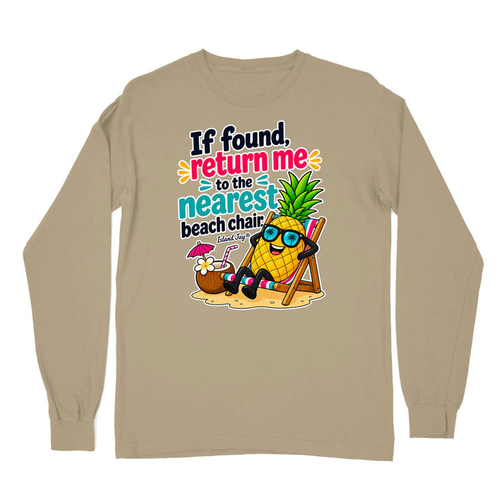 A beige long-sleeve t-shirt with a colorful graphic print on the front. The graphic features a cartoon pineapple wearing sunglasses and sitting in a beach chair next to a cocktail, with the text 'If found, return me to the nearest beach chair' and 'Eternal Dog'.