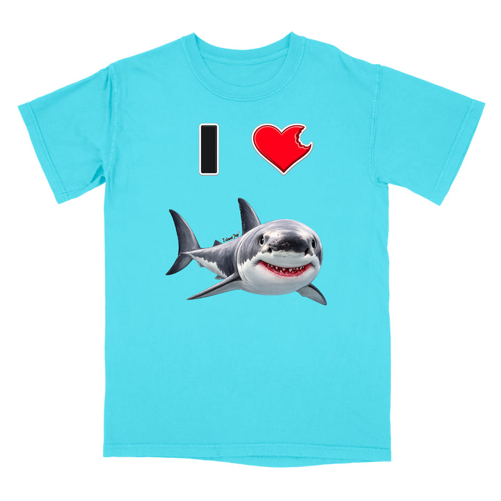 A light blue short-sleeve crewneck t-shirt featuring a graphic print of a great white shark below a text design that reads 'I' followed by a red heart and the shark.