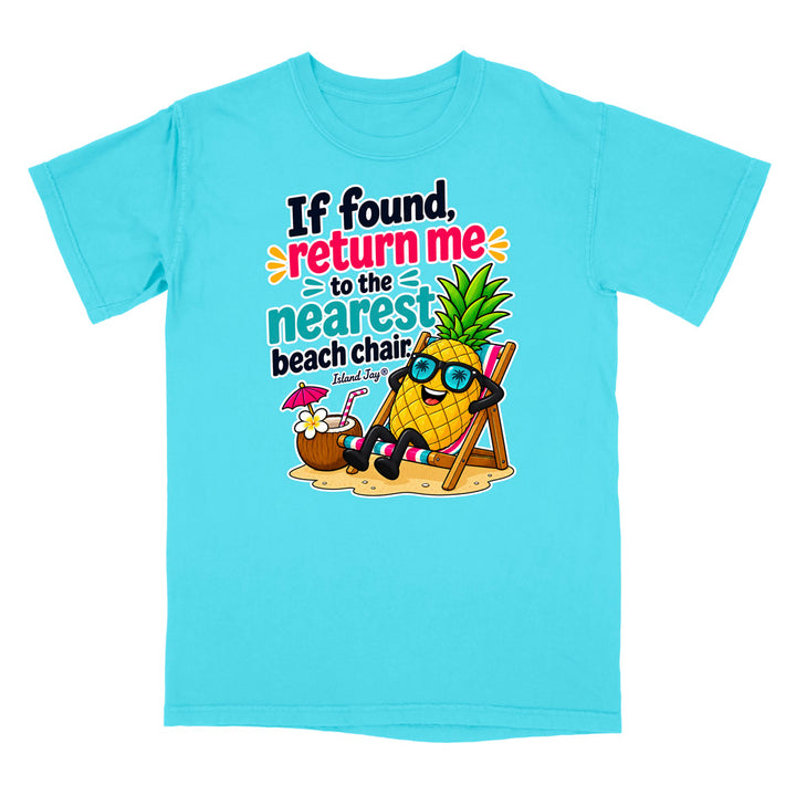 A light blue short-sleeve crewneck t-shirt featuring a colorful graphic of a pineapple wearing sunglasses and relaxing in a beach chair next to a coconut drink, with the text 'If found, return me to the nearest beach chair' and 'Shark Rayz' printed on the front.
