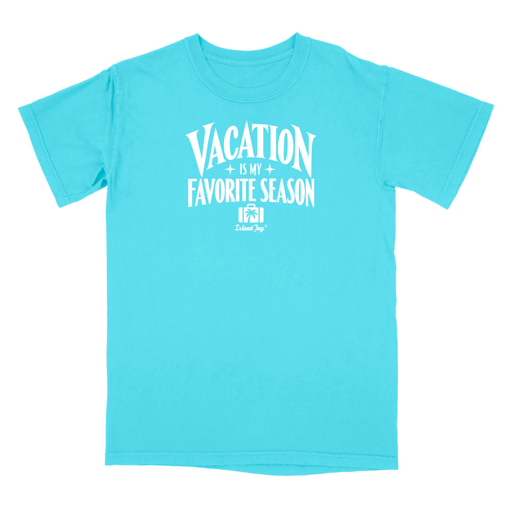 A bright turquoise short-sleeve t-shirt with a white graphic print on the front that reads 'VACATION IS MY FAVORITE SEASON' with a small 'Deluxe Dog' logo underneath, displayed on a solid white background.