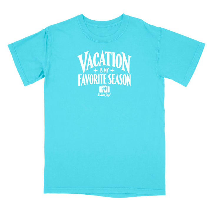 A bright turquoise short-sleeve t-shirt with a white graphic print on the front that reads 'VACATION IS MY FAVORITE SEASON' with a small 'Deluxe Dog' logo underneath, displayed on a solid white background.