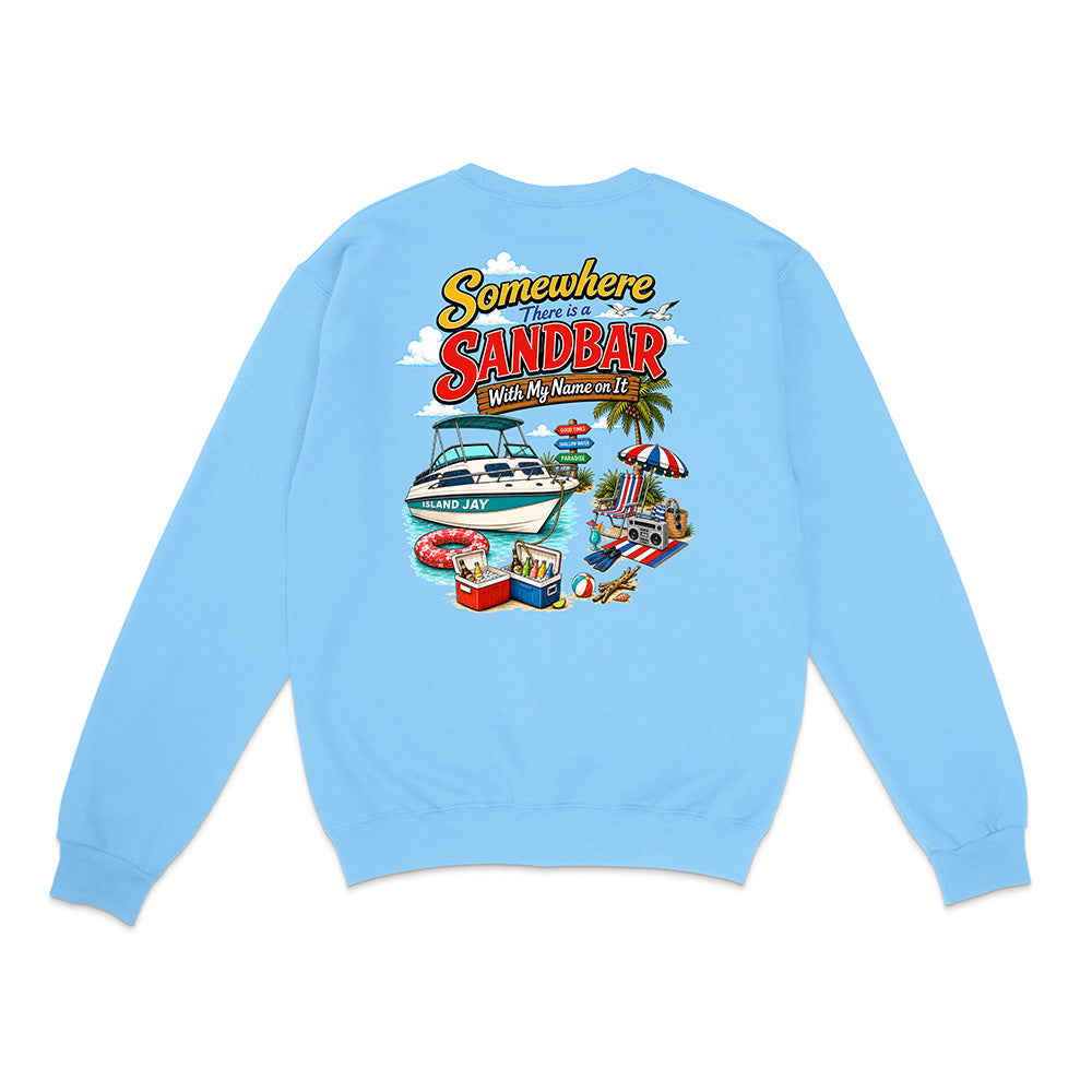 A light blue crewneck sweatshirt shown from the back, featuring a colorful graphic print with the text 'Somewhere I've Been ISLAND' and an illustration of a boat, beach umbrella, palm tree, and poolside scene.